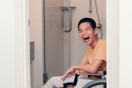 A laughing young man in a modern bathroom, symbolising the dignity and peace of mind found in independent living.